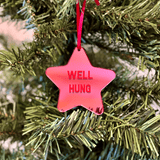 a pink star ornament hanging from a christmas tree