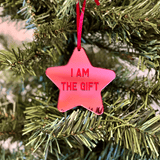 a pink star ornament hanging from a christmas tree