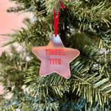 a pink star ornament hanging from a christmas tree