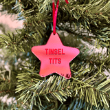 a pink star ornament hanging from a christmas tree